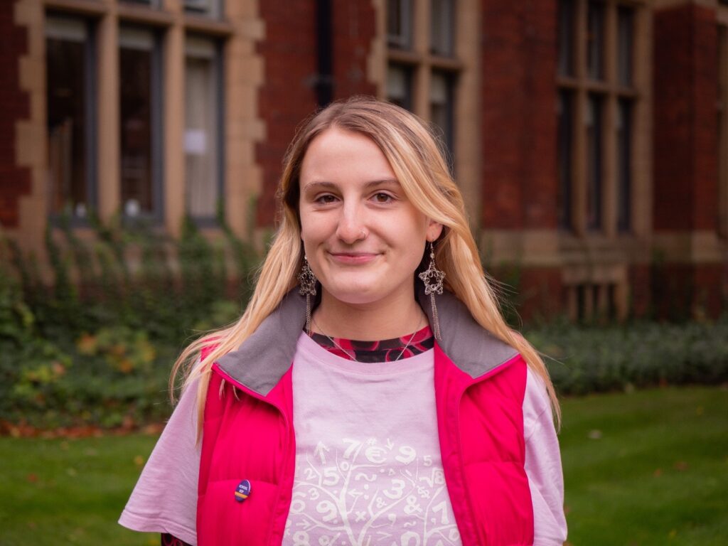 A woman with blonde hair wearing a pink coat