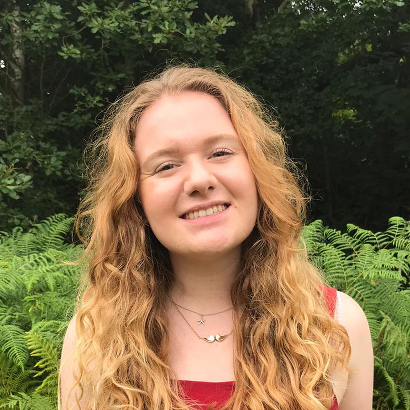 A woman with blonde curly hair is smiling at the camera. 